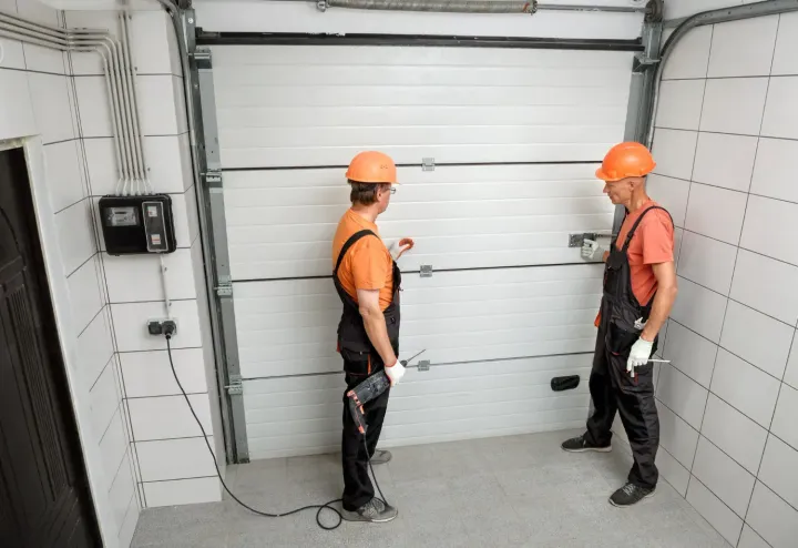 Two technicians adjusting a garage door track bracket during installation in Surprise, AZ
