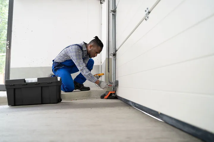 Technician testing a garage door safety sensor and bottom track at a North Phoenix, AZ home