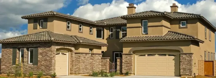 Large stucco and stone two-story home with an arched double garage door in a Peoria, AZ master-planned community