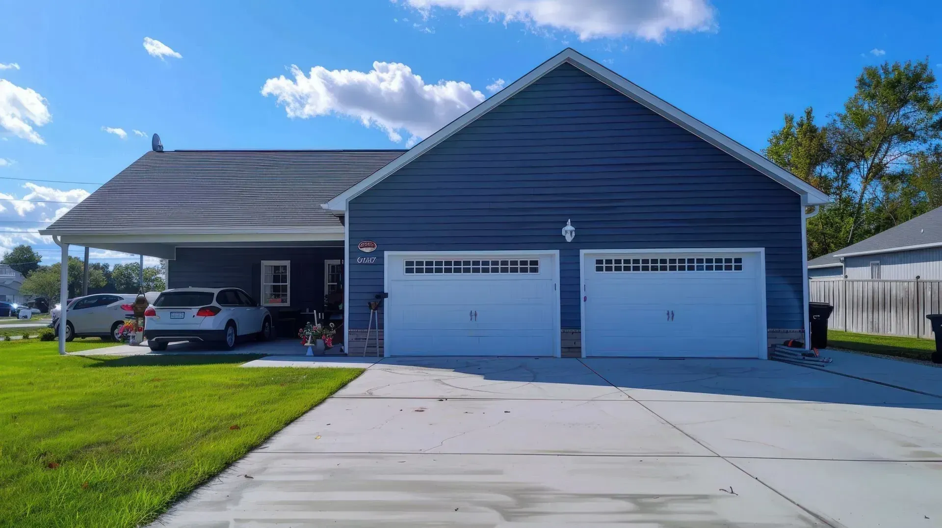 Navy-sided Glendale, AZ home with two white sectional garage doors and a wide concrete driveway