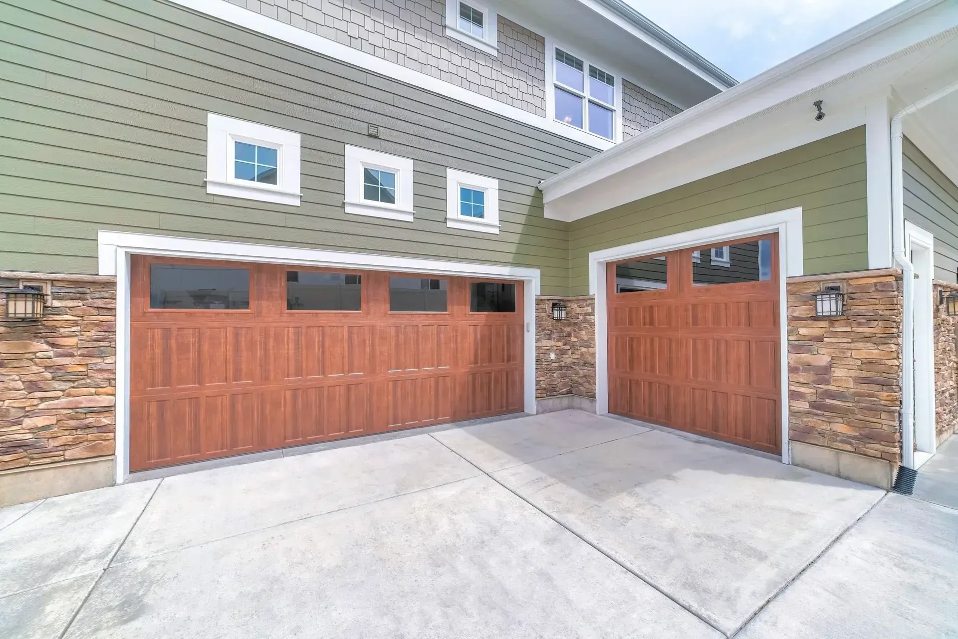Newer two-story Peoria, AZ home with stone accents and two wood-tone garage doors on a split driveway