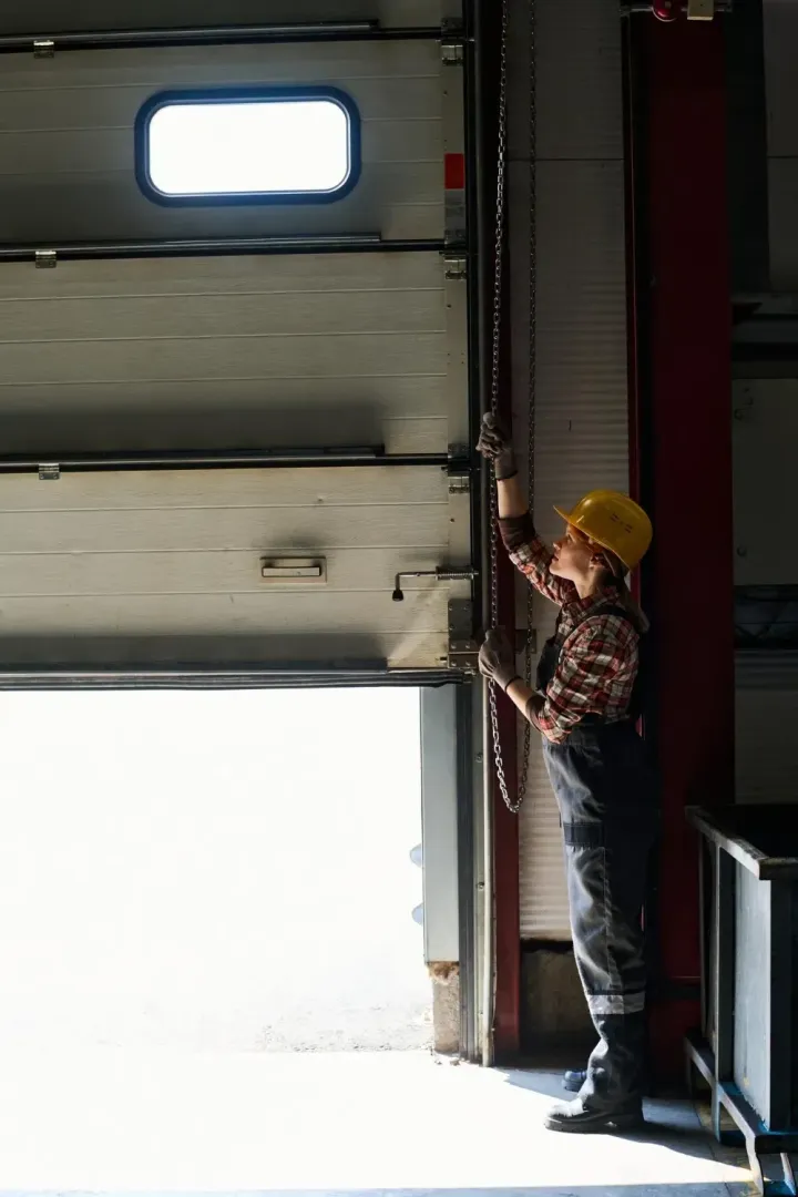 Technician pulling a manual chain hoist to test spring tension on a partly raised Glendale, AZ garage door