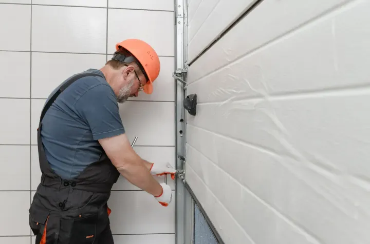 Technician adjusting a garage door track bracket during repair